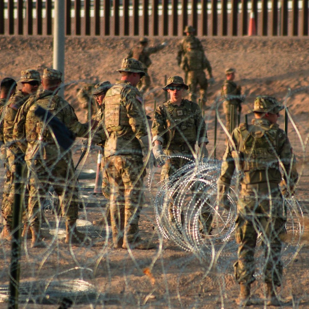 Elementos del ejército de EUA refuerzan con alambre con púas donde migrantes de diversas nacionalidades esperan.